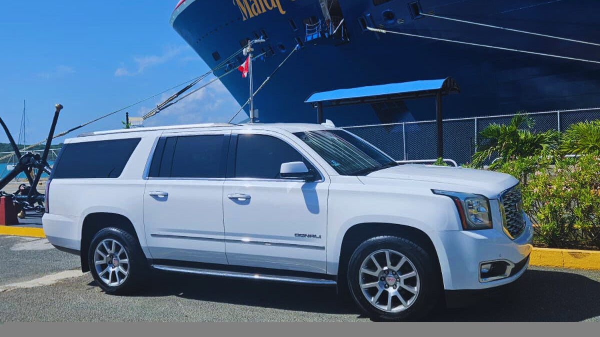 White SUV in front of a cruise ship with 'Mardi Gras' on its side.